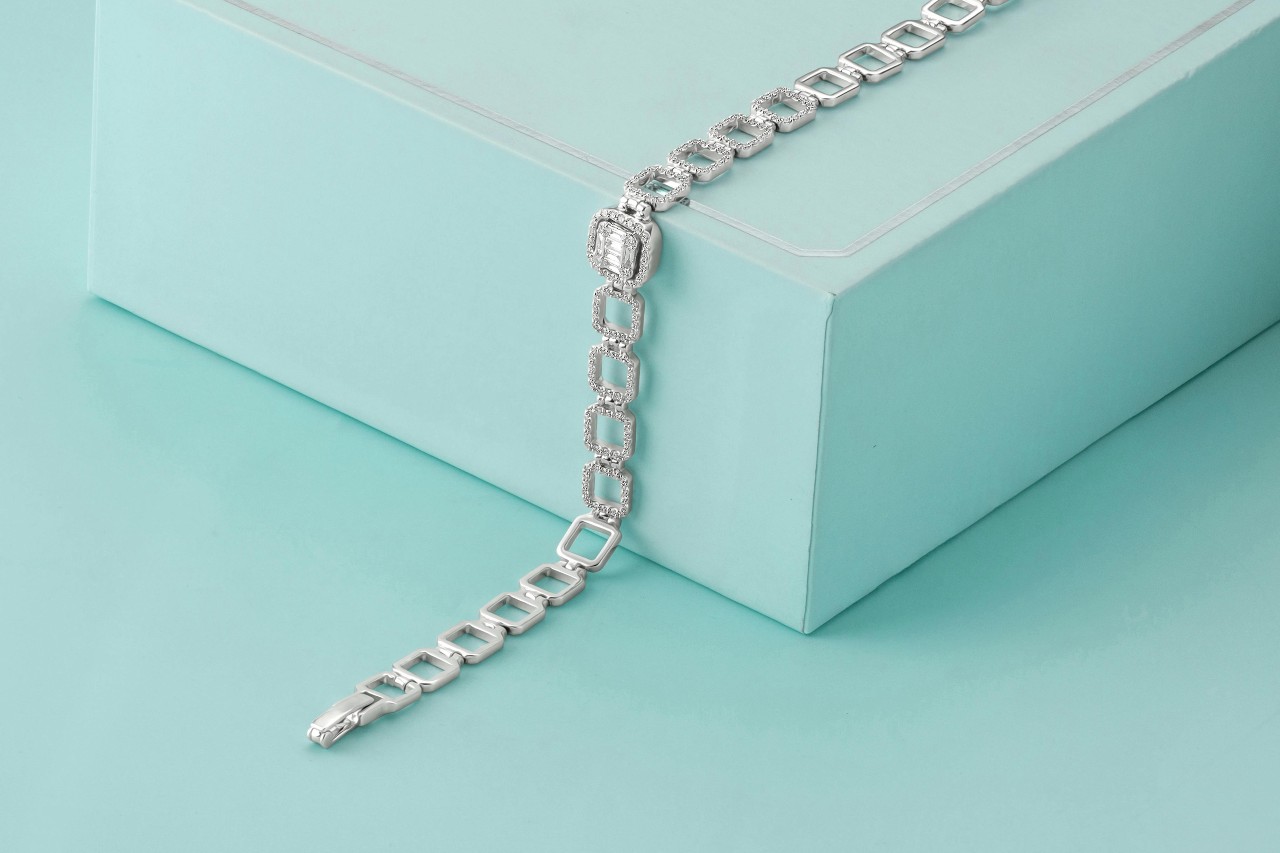 A white gold diamond line bracelet lying across a light blue gift box.