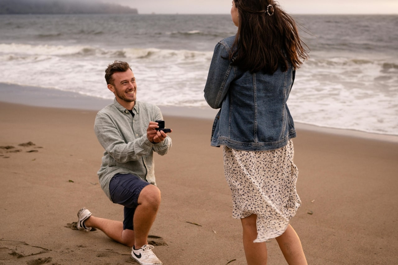 A guy proposing to a woman on the beach