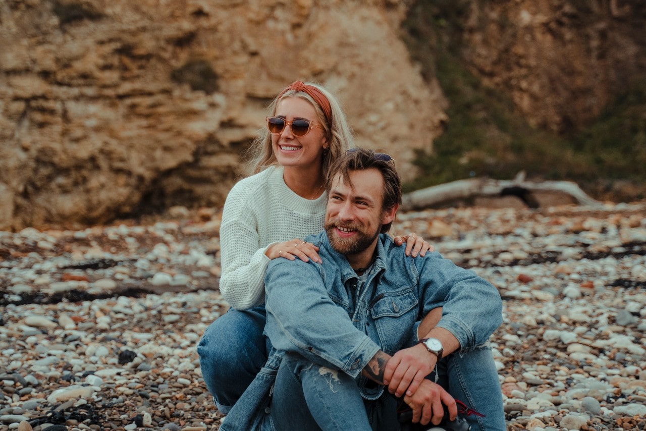 A comfortably dressed couple wearing modest jewelry at the seaside.