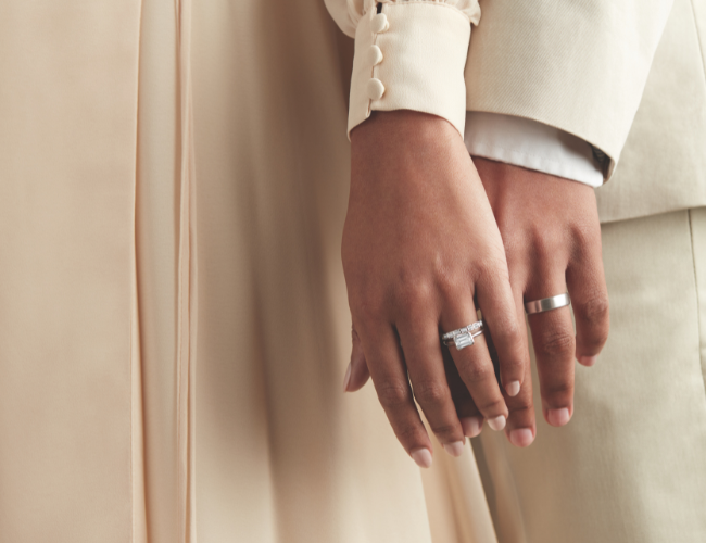 A photo of a couple’s hands showcasing their bridal rings