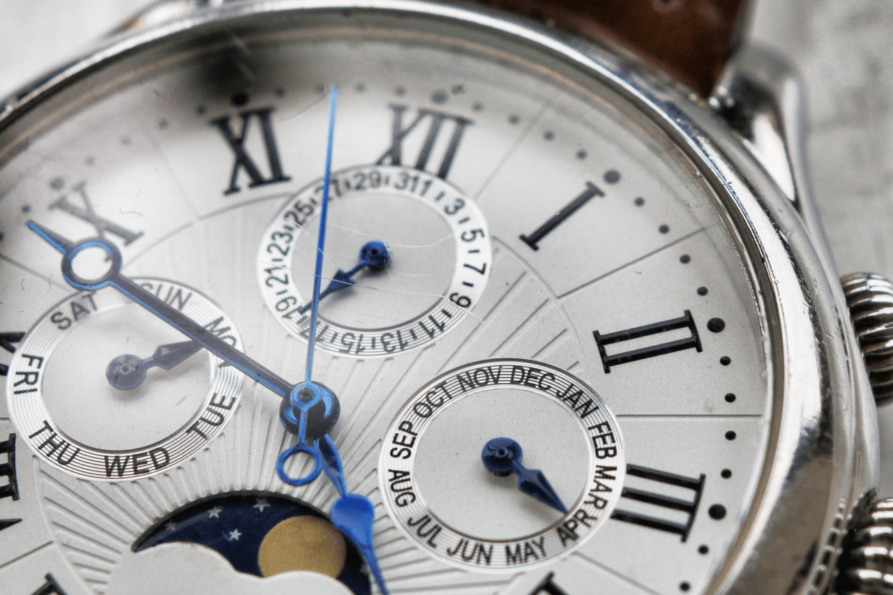 A close-up of a watch with three date complications and a moon phase complication in the dial’s center.