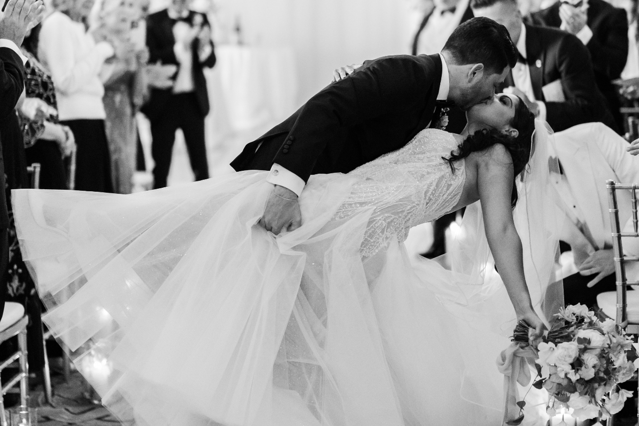 a bride and groom embracing at the altar at a beach wedding beside a natural material archway