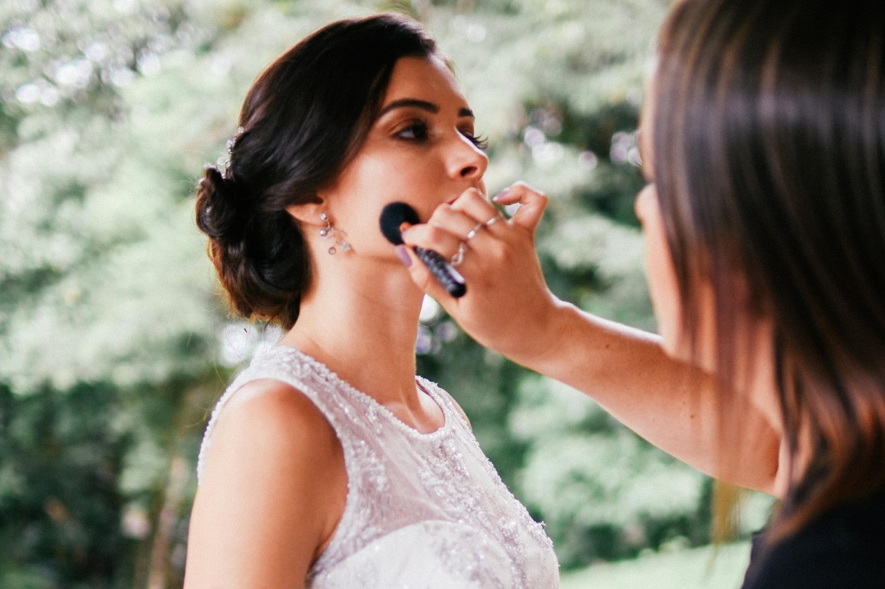 a bride getting her makeup done on her wedding day outside