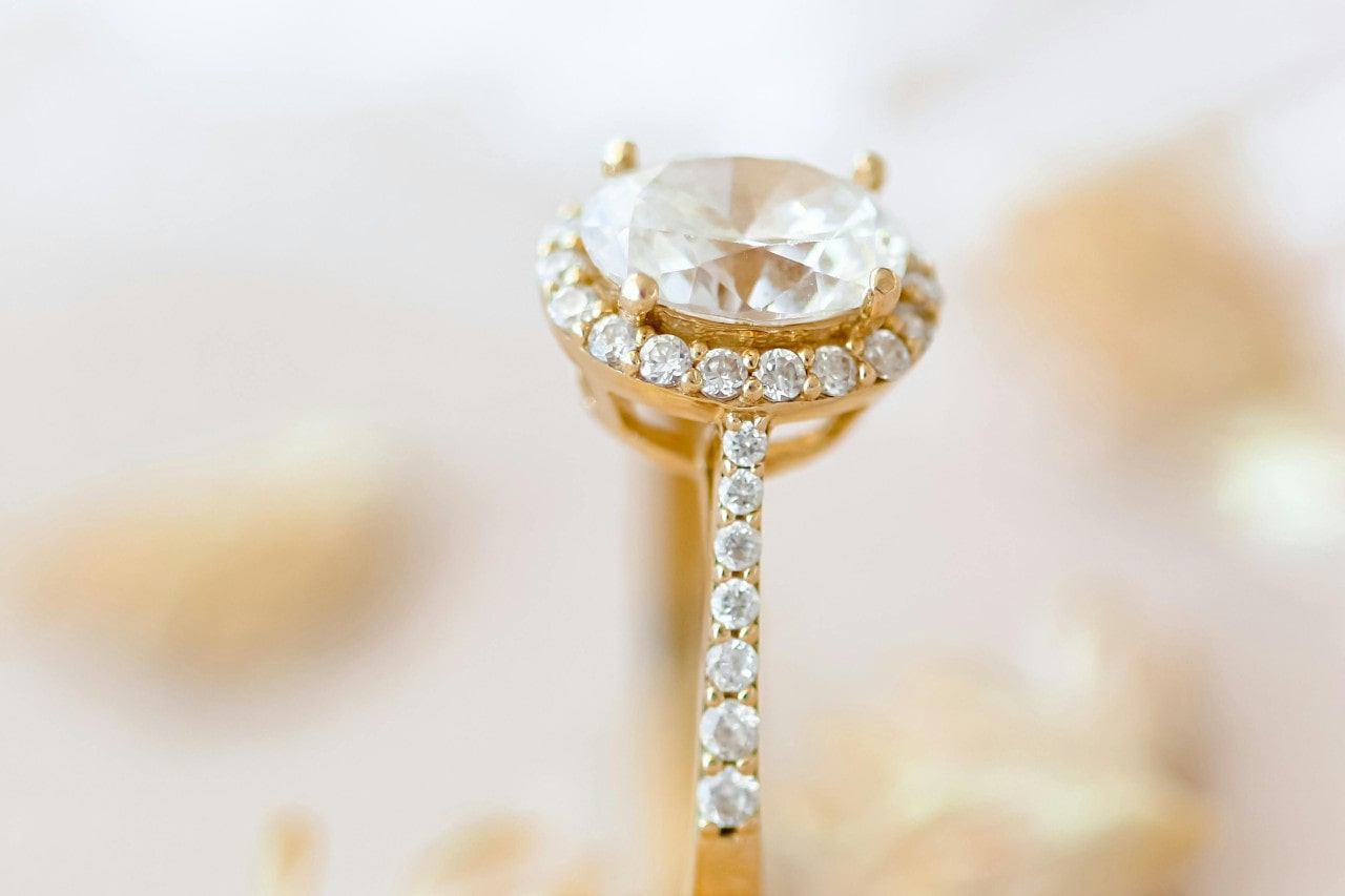 a yellow gold engagement ring featuring an oval cut center stone