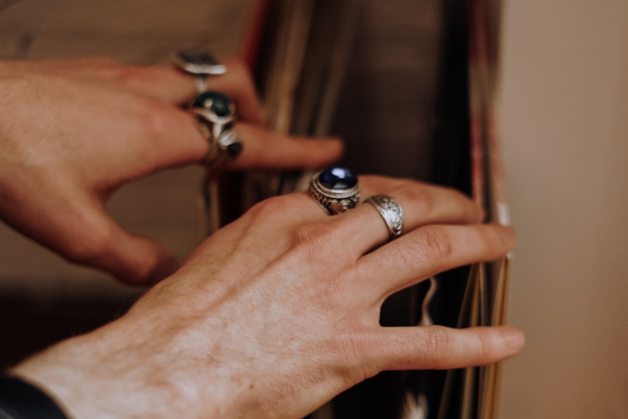 a person’s hands looking through records wearing sculptural silver fashion rings