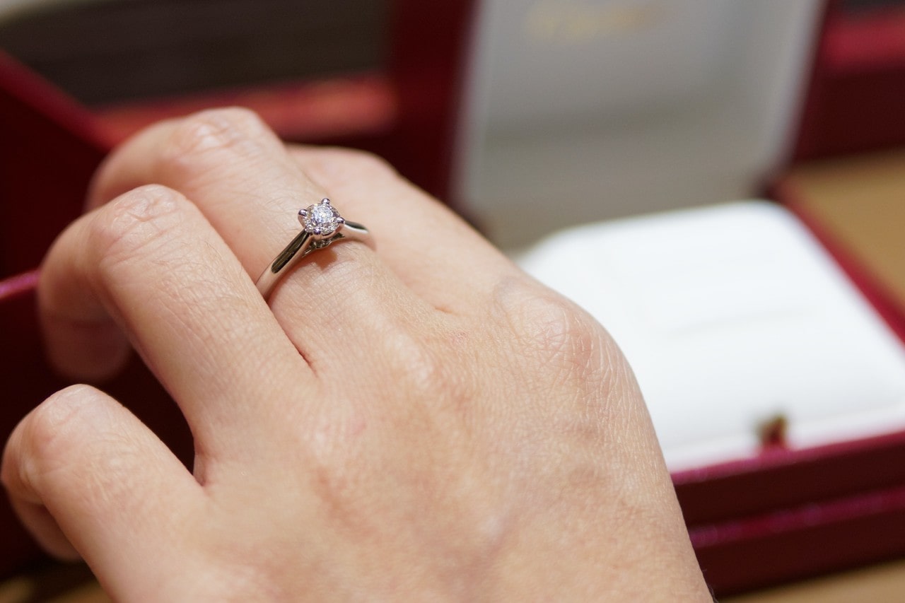 A close-up of a woman’s hand wearing a single, elegant solitaire ring.