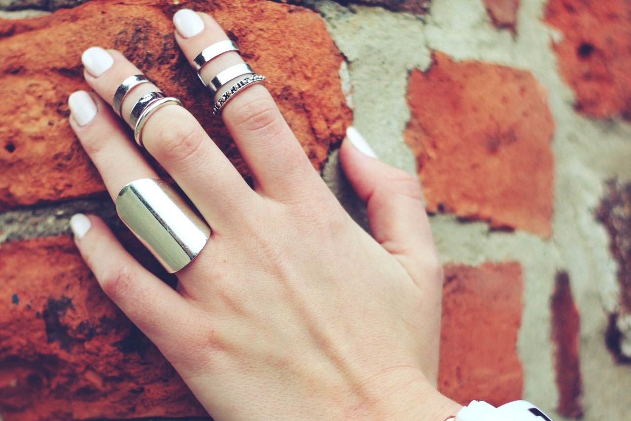 A close-up of a woman’s hand adorned with many bold rings.