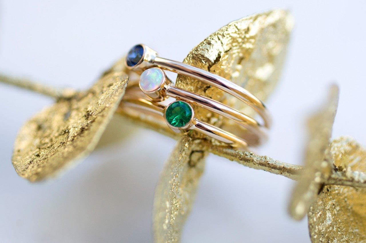 A close-up of a stylish gemstone ring displayed atop a gold laurel.