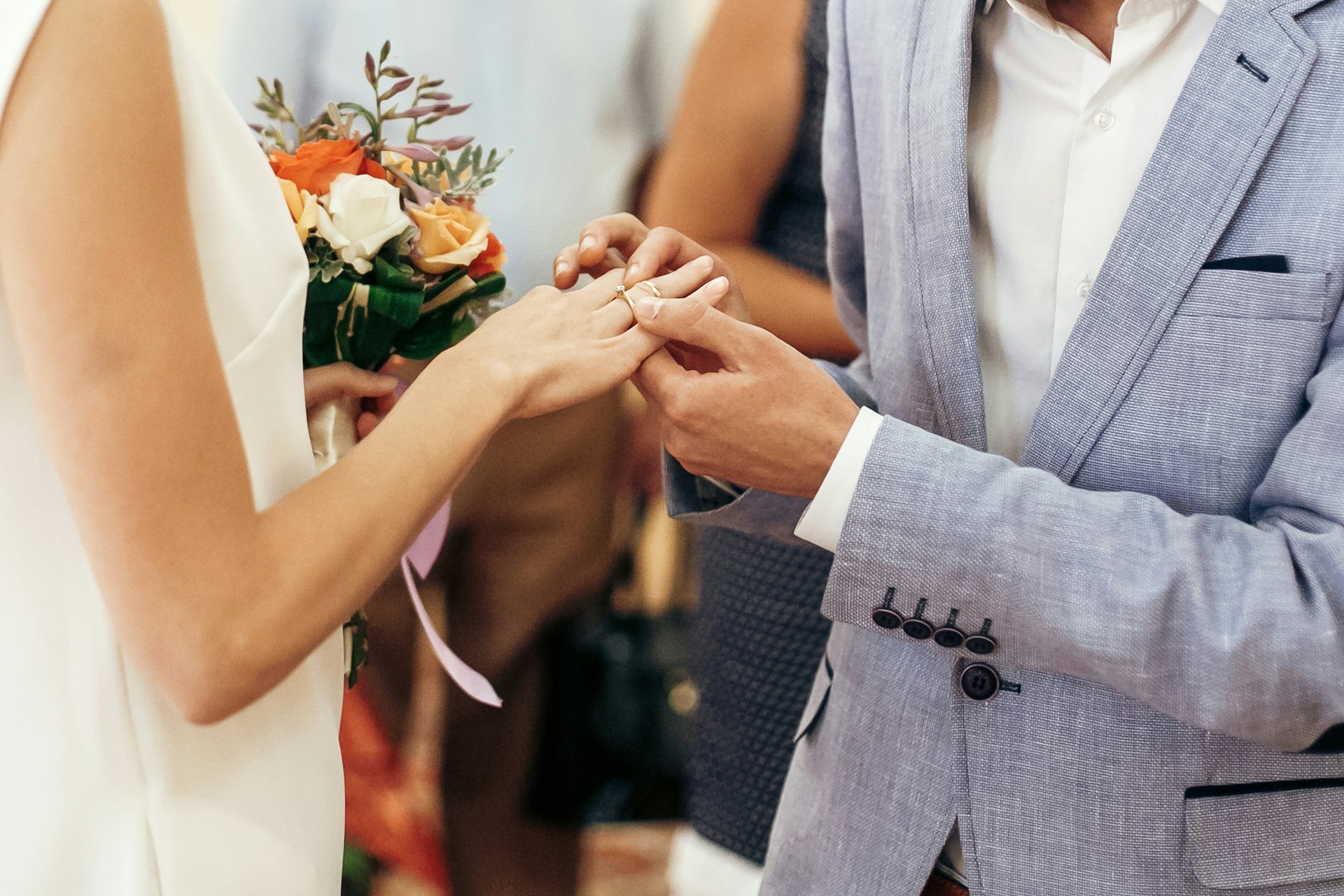 A groom placing a wedding band on his bride’s finger.