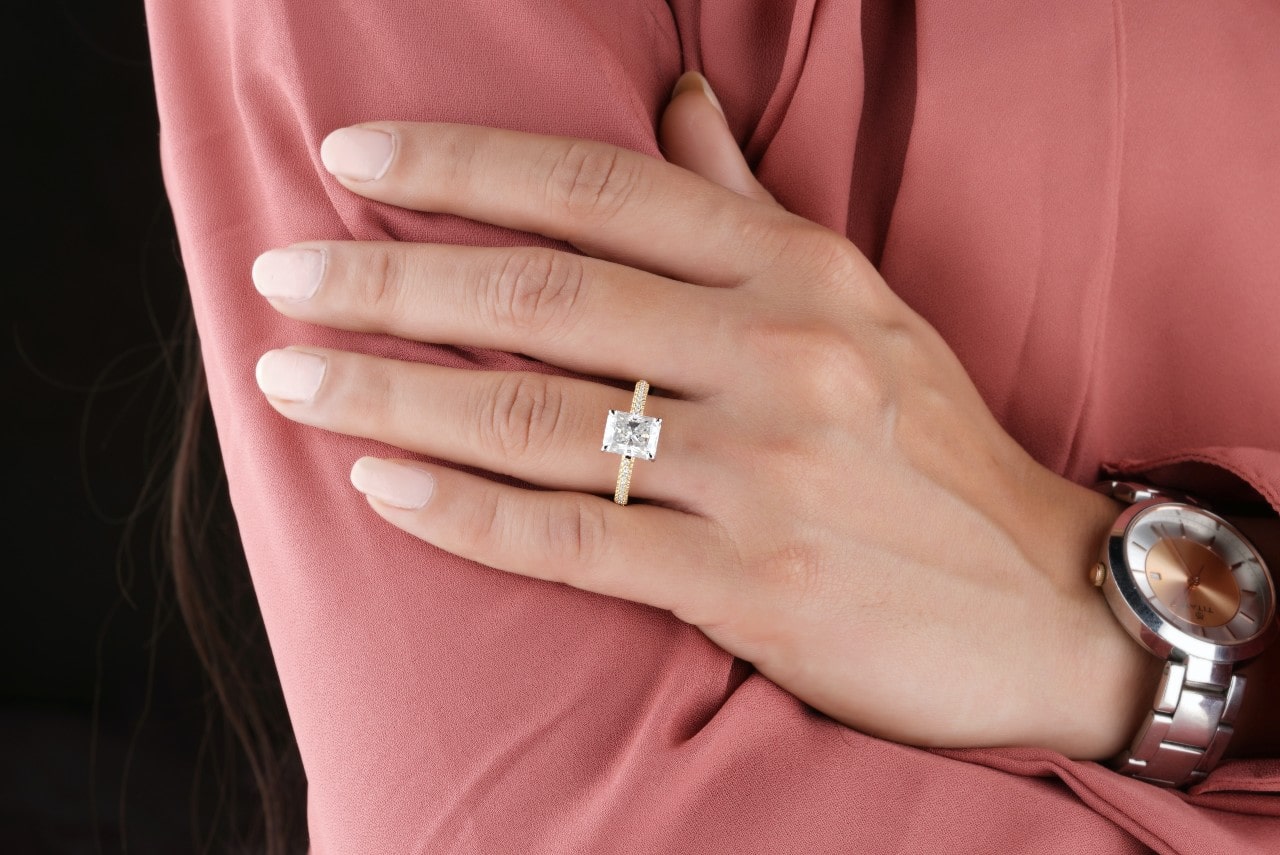 woman wearing rectangle cut side stone enagement ring