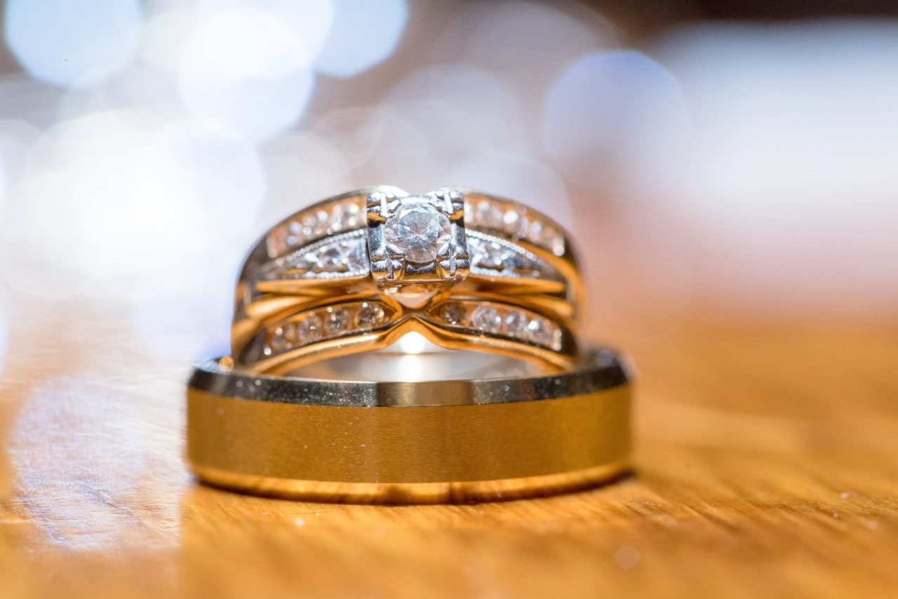 A close-up of two pristine white gold wedding bands on a wooden surface.