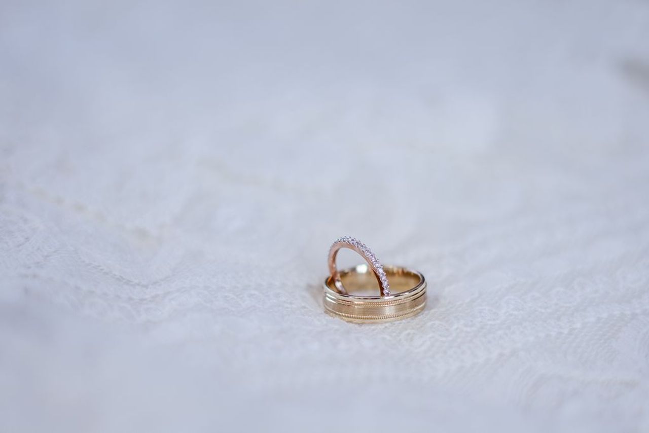 Two gold wedding bands resting on pristine white lace.